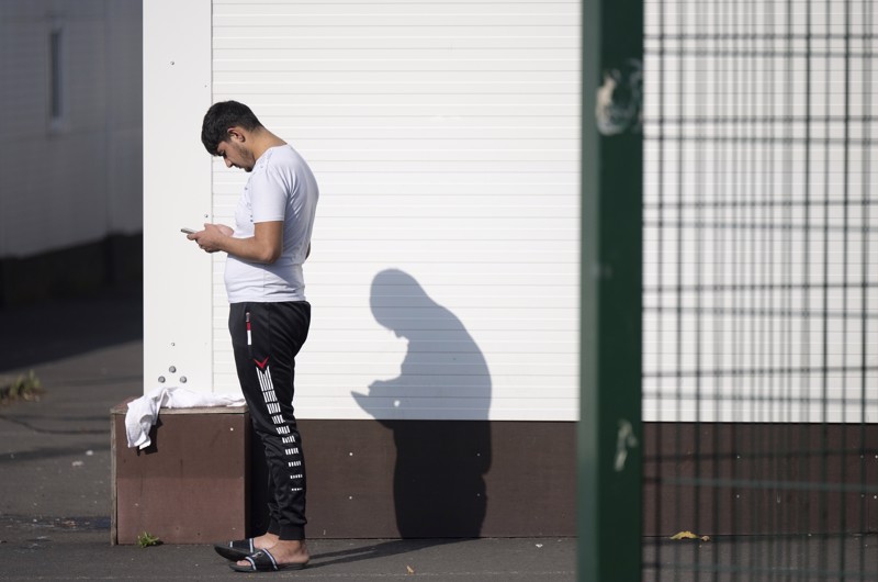 Ein Asylbewerber steht vor einem Wohncontainer.