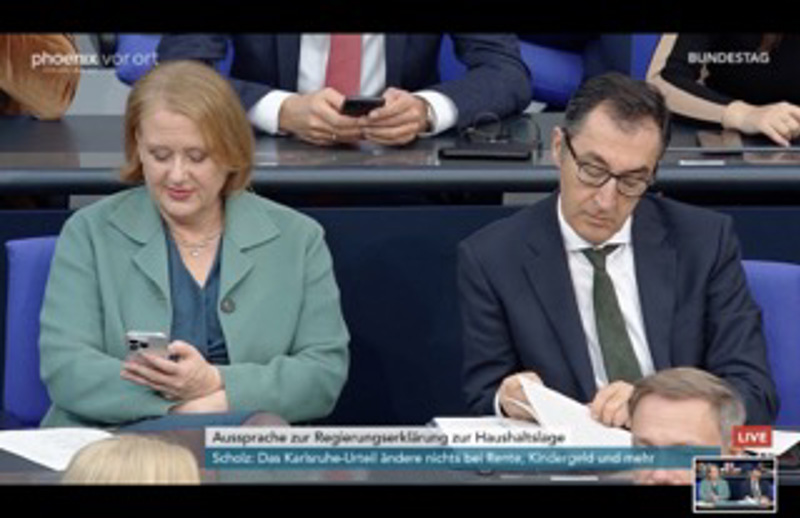 Ministerin Lisa Paus spielt am Handy, Minister Özdemir liest.