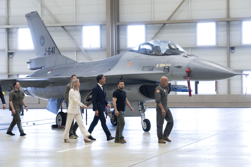 Wolodymyr Selenskyj (2.v.r), Präsident der Ukraine, und Mark Rutte (M), Ministerpräsident der Niederlande, laufen an einem F-16 Kampfjet vorbei.