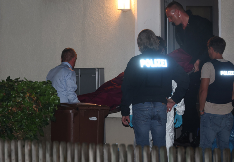 Beamte tragen eine Leiche aus dem Haus