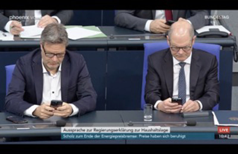 Habeck und Scholz sind beide in wichtige Textnachrichten vertieft.